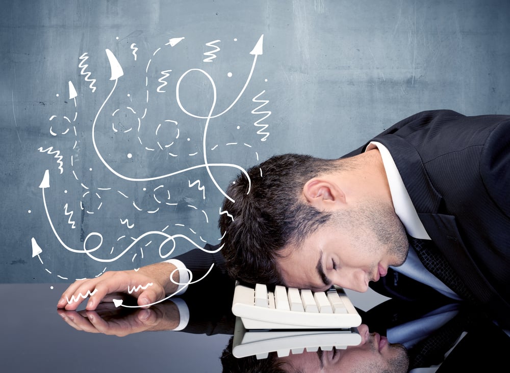 A depressed businessman resting his head on a keyboard and shouting with illustration of ideas, arrows, lines leaving his head concept