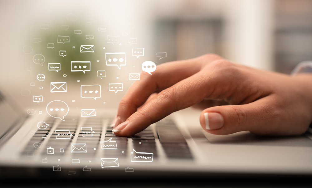 Business woman hand typing on keyboard with chat icons around