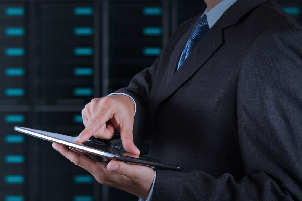 businessman hand using tablet computer and server room background