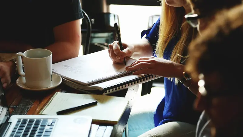 woman with notebook, man with coffee in a meeting