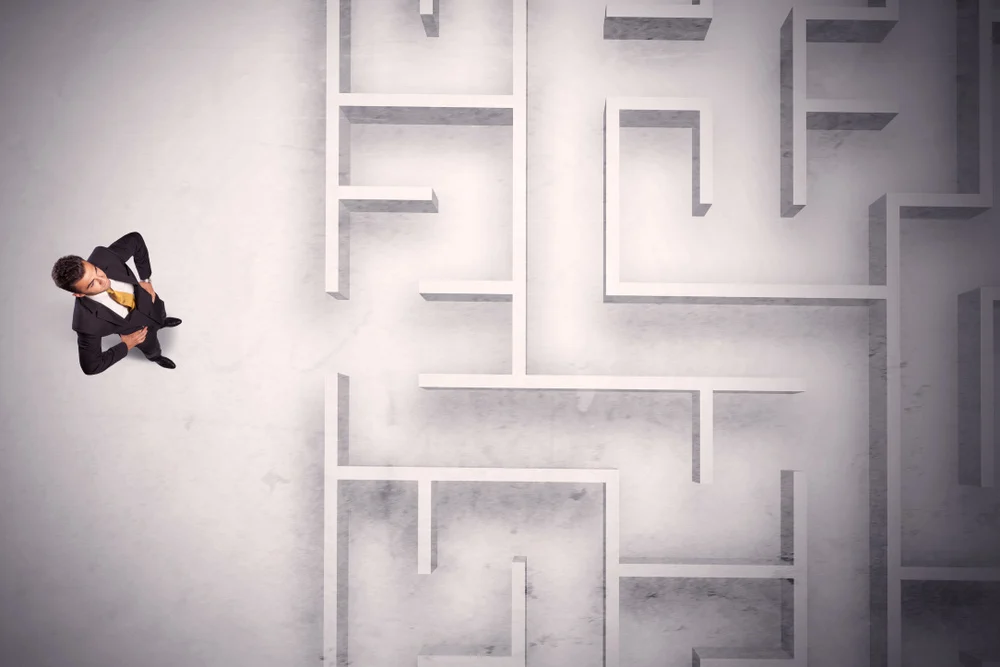 Confused businessman standing at a maze wall with grungy background