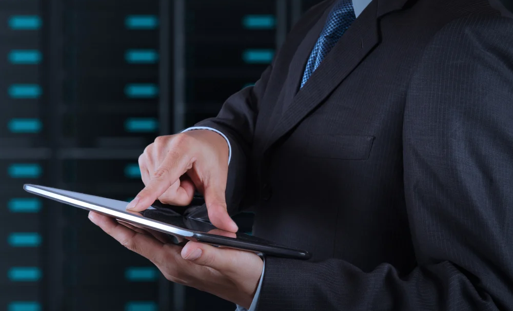 businessman hand using tablet computer and server room background