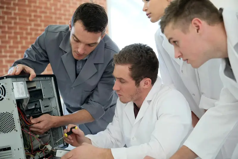 Students in computing class with teacher fixing hardware