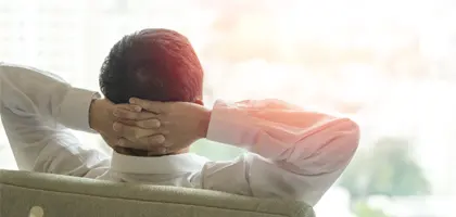 man relaxing with hands behind head